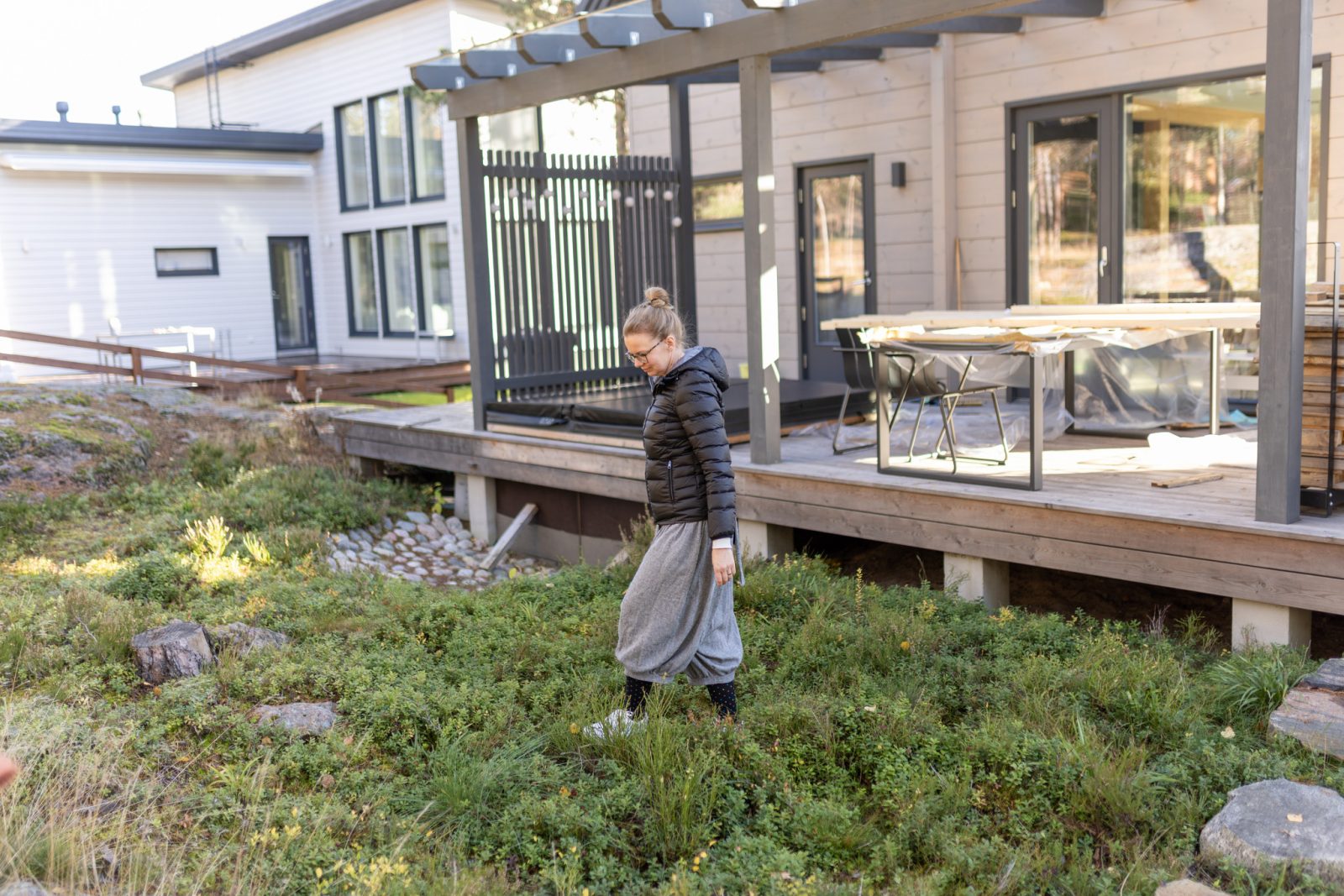 Nainen kävelee rakentamansa talon takapihalla avautuvalla marjamättäällä.