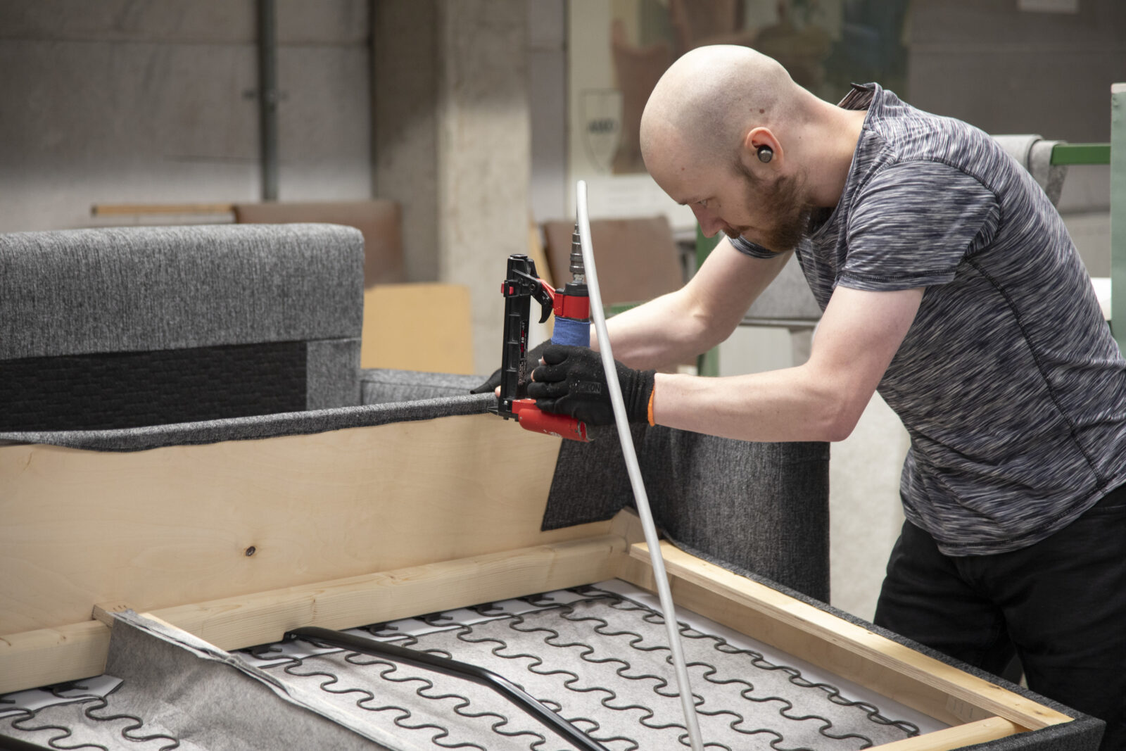 Mies työskentelee sohvan verhoilun parissa Askon tehtaassa.
