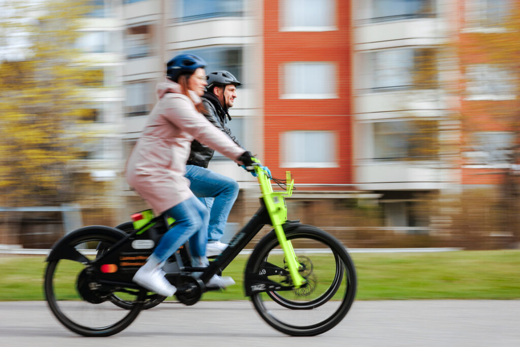 Kaksi henkilöä ajaa kaupunkipyörillä.