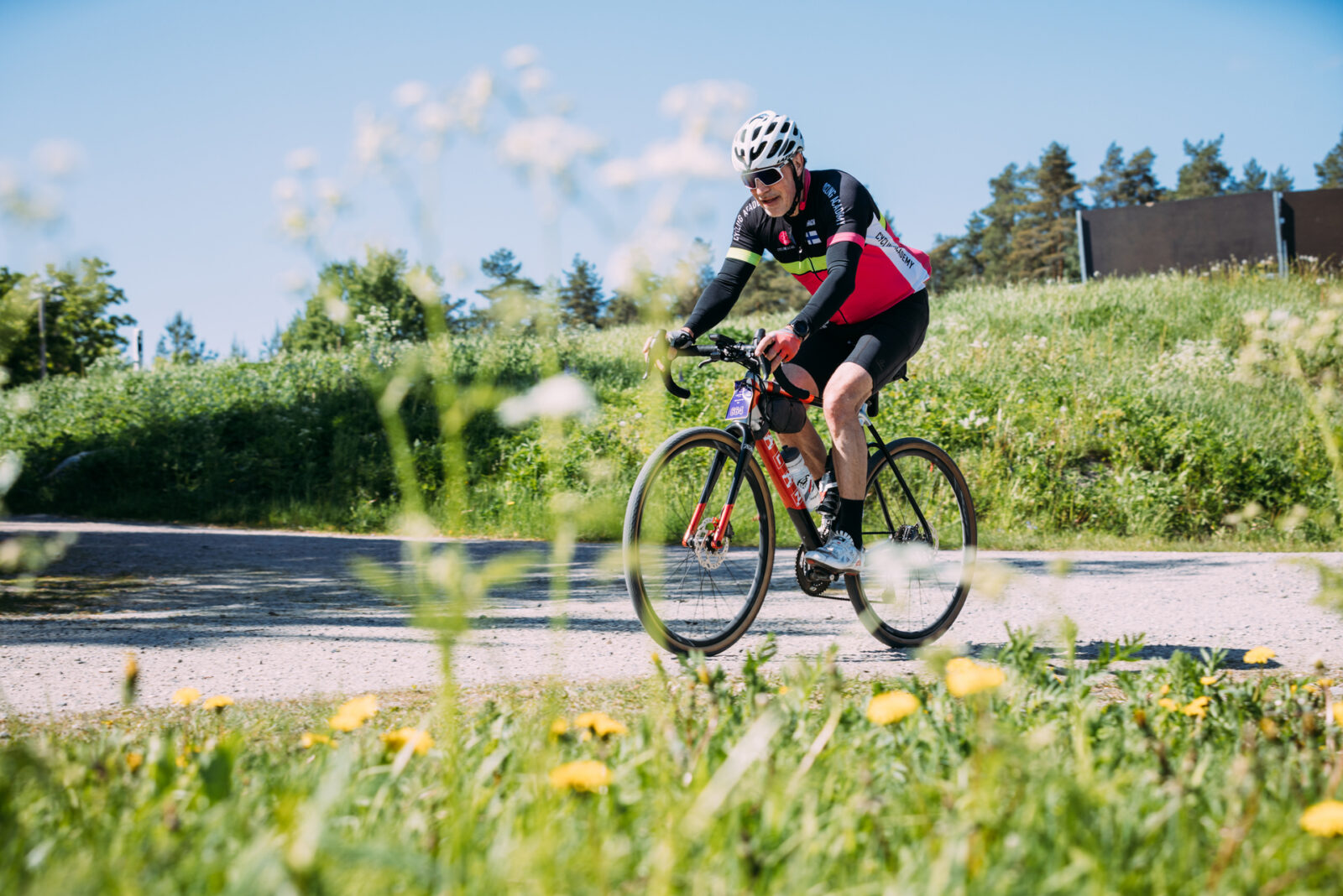 Mies pyöräilee kesäisen vehreässä ympäristössä.