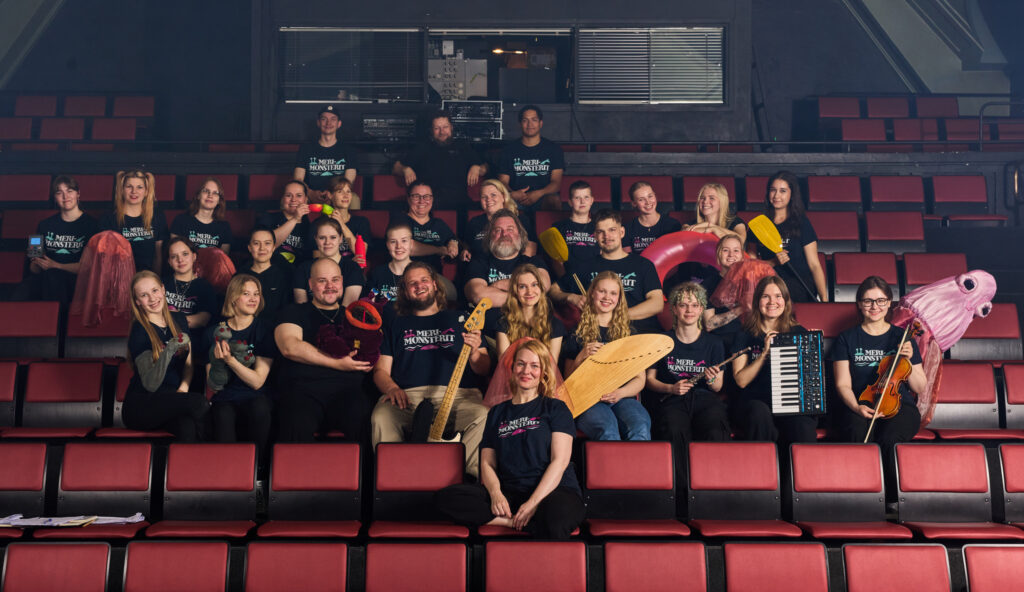 Kuvassa Lahden Kesänäyttämön tiimi istuu teatterin katsomossa.