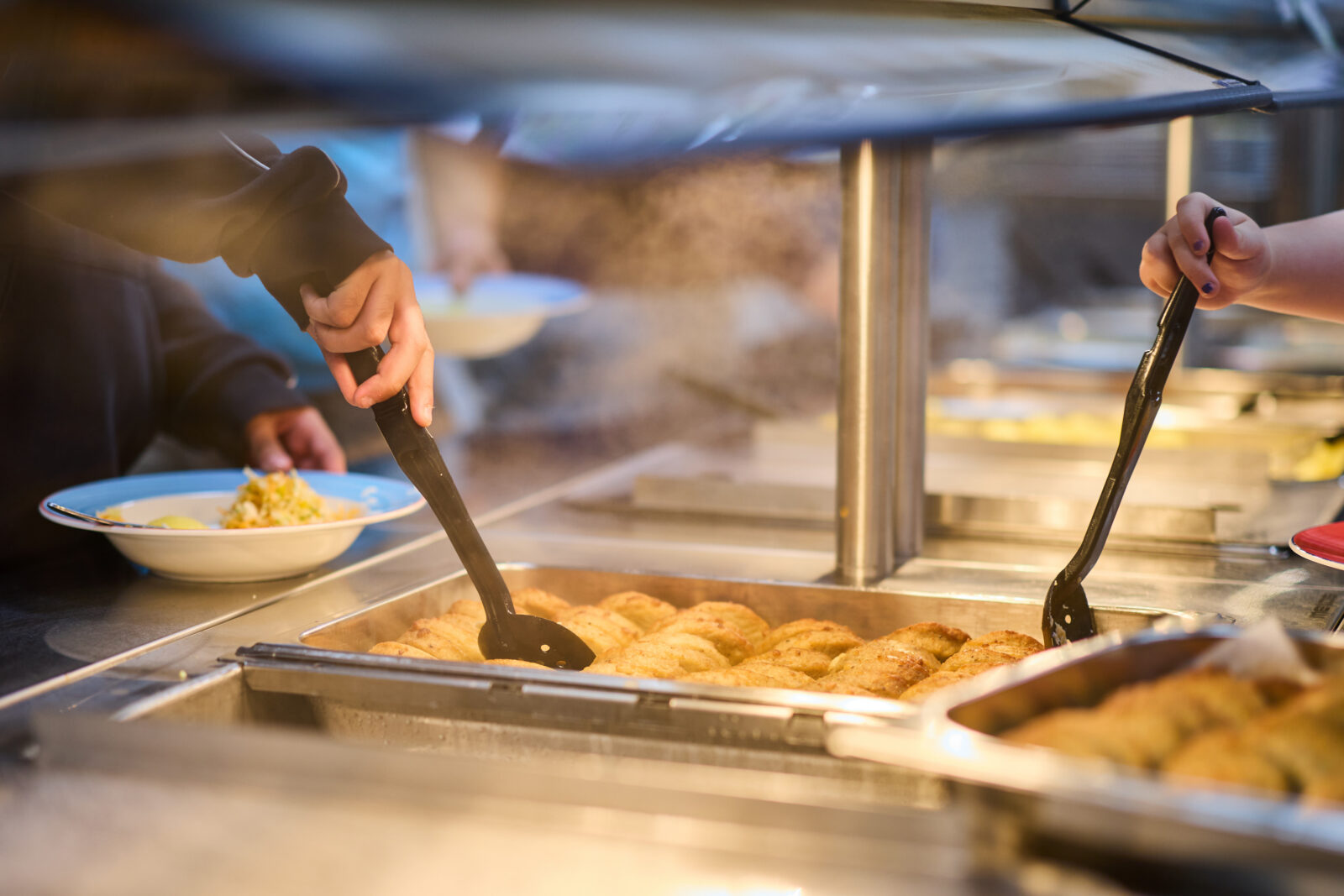 Lapset ruokalinjastolla ottamassa kalapihvejä lautaselleen.