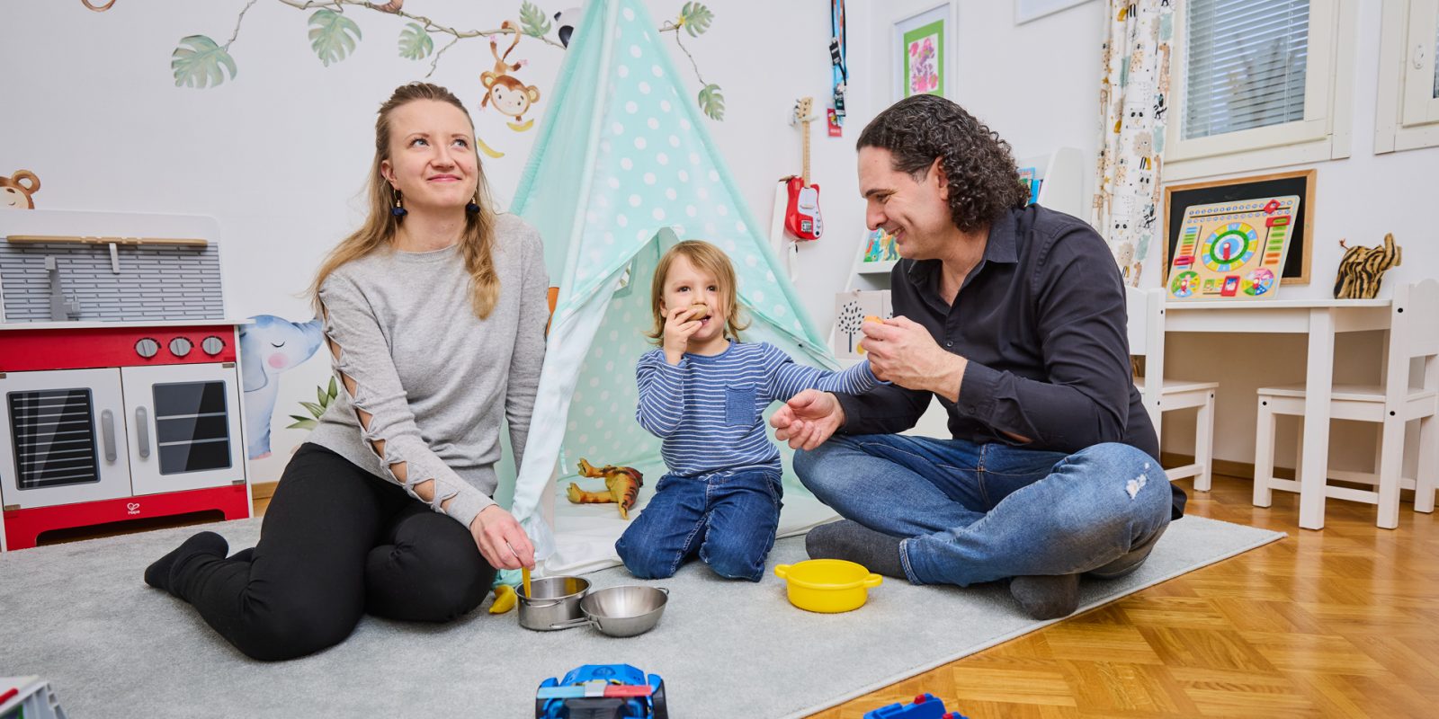 Perhe leikkii huoneen lattialla.