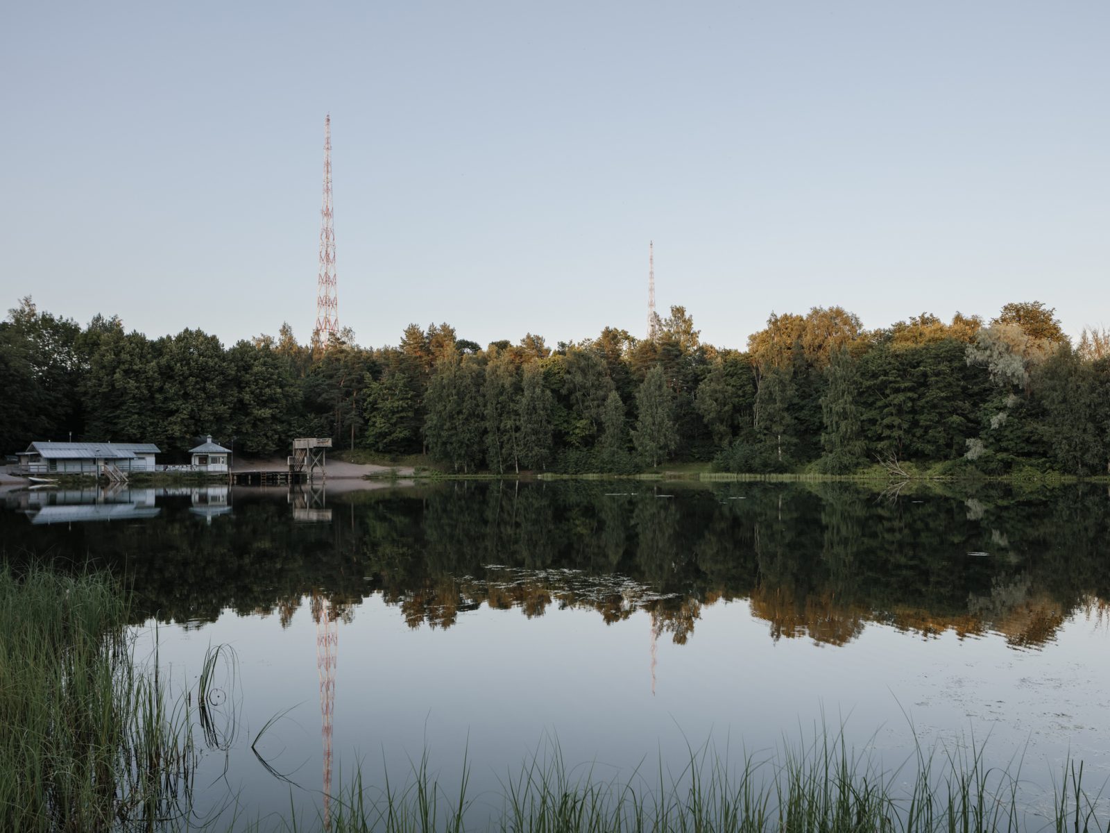Mytäjäisten ranta tyynenä kesäiltana. Vastarannalla näkyvät laituri, hyppytori ja pukuhuone. Taustalla Lahden radiomastot.