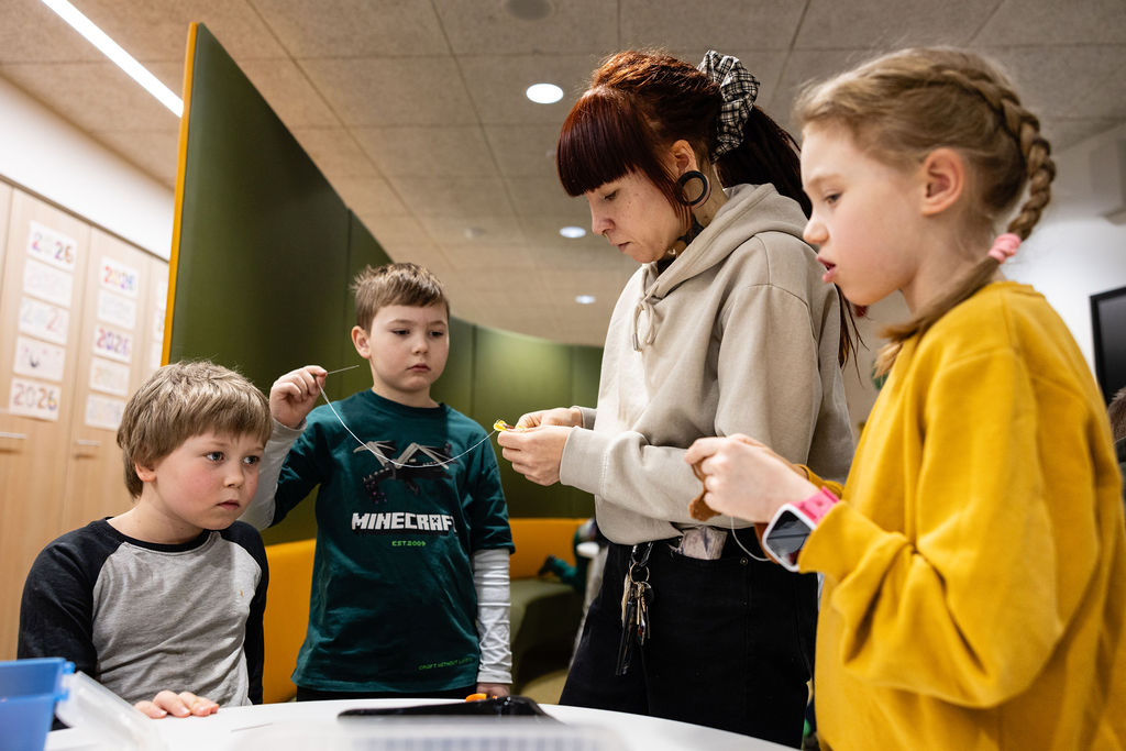 Lapsia ohjaajan kanssa askartelemassa