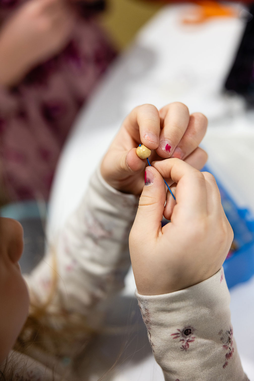 Tehdään koruja, pujotetaan helmi lankaan