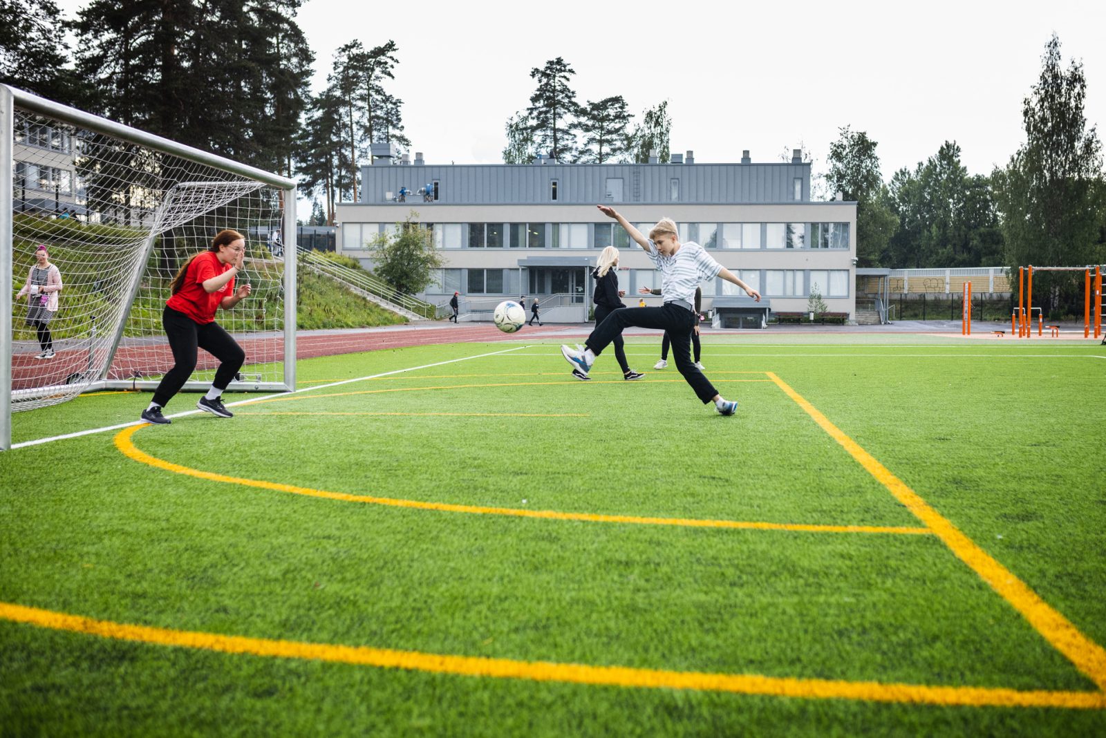 Kuvassa nuoret potkivat jalkapalloa Kärpäsen koulun tekonurmikentällä.