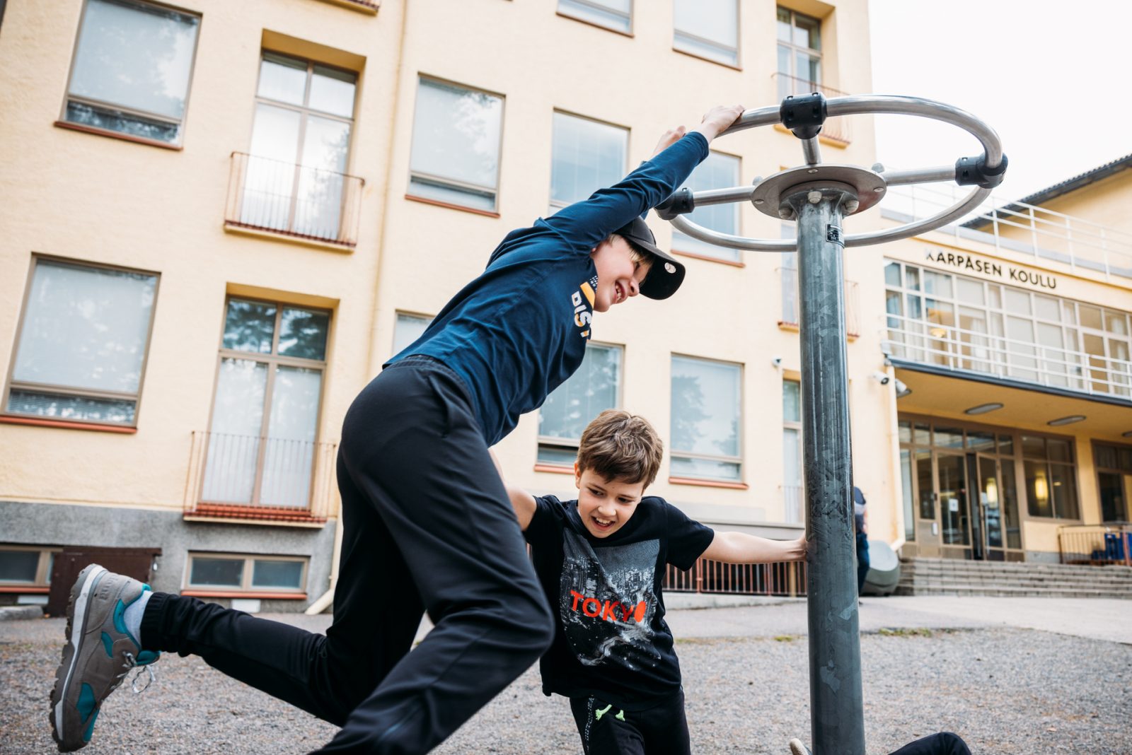 Lapsia roikkumassa ja temppuilemassa telineessä koulun pihassa.