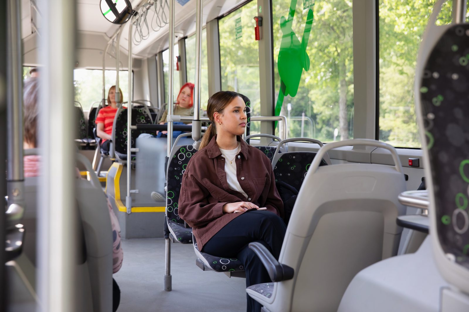 Opiskelija istuu linja-auton kyydissä ja katselee ulos ikkunasta