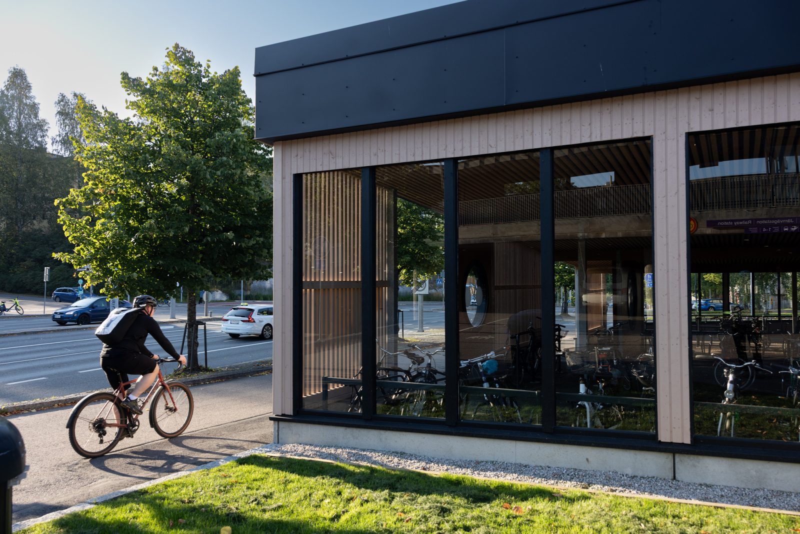 Mies ajaa Uudenmaankadun pyörätietä kohti uutta puuverhoiltua pyöräkatosta