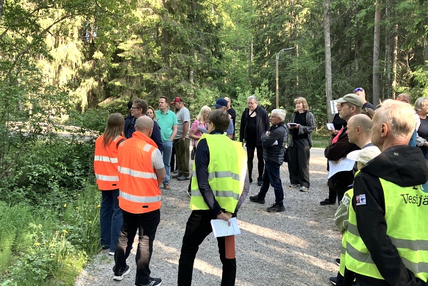 Asukkaat kokoontuneena Vuorenrinteentielle kuulemaan Ahtialan Selkätien suunnitelmista. Ympärillä on vihreää metsää.