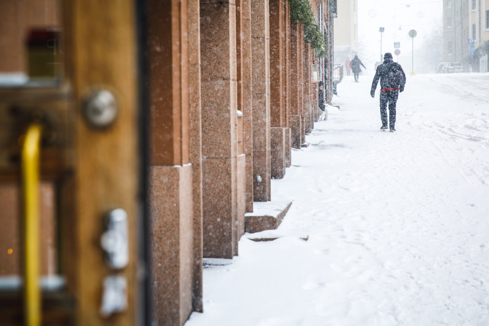 Henkilö kävelee lumisella kadulla.