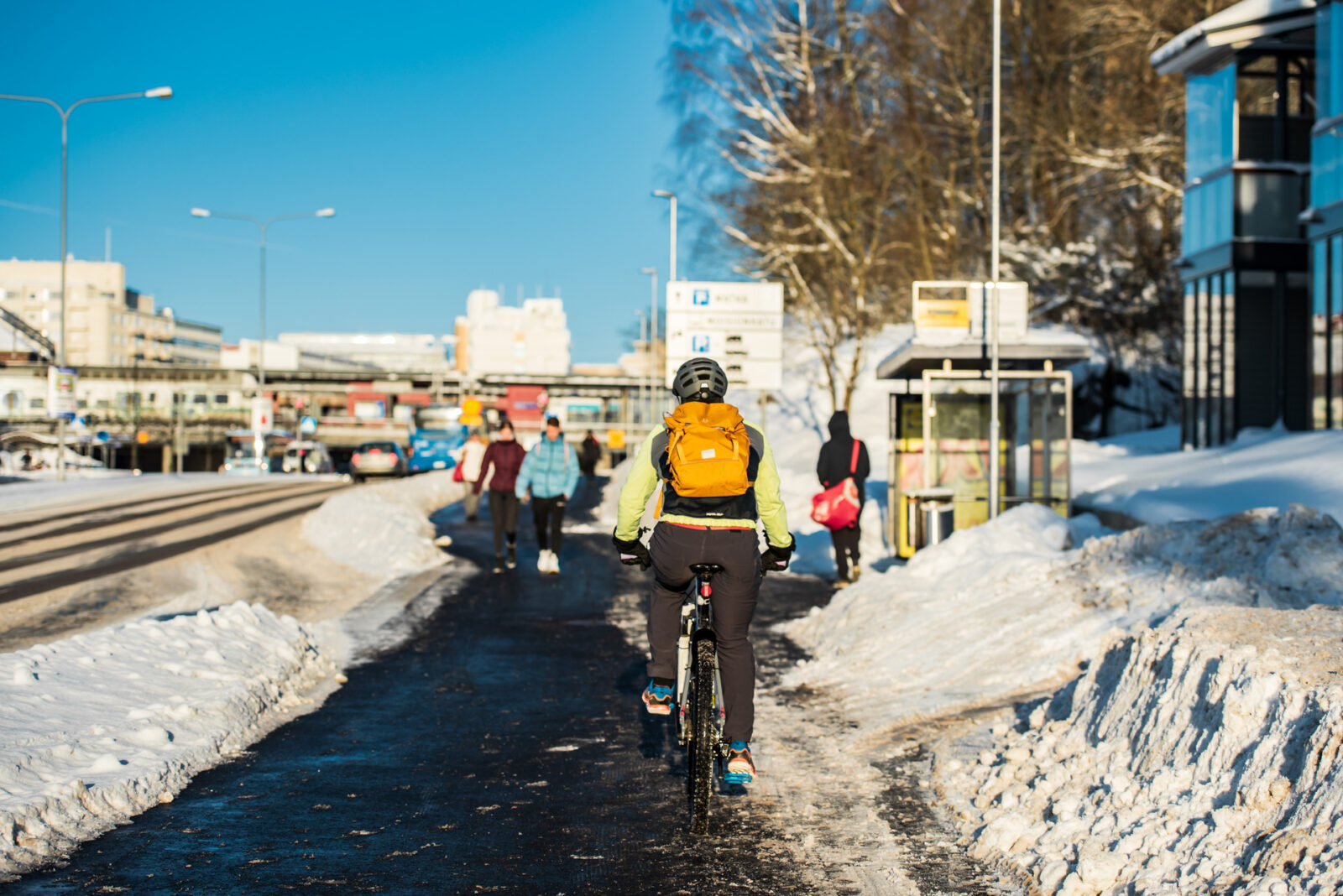 Pyöräilijä ajaa pyörätiellä. Taustalla bussipysäkki.