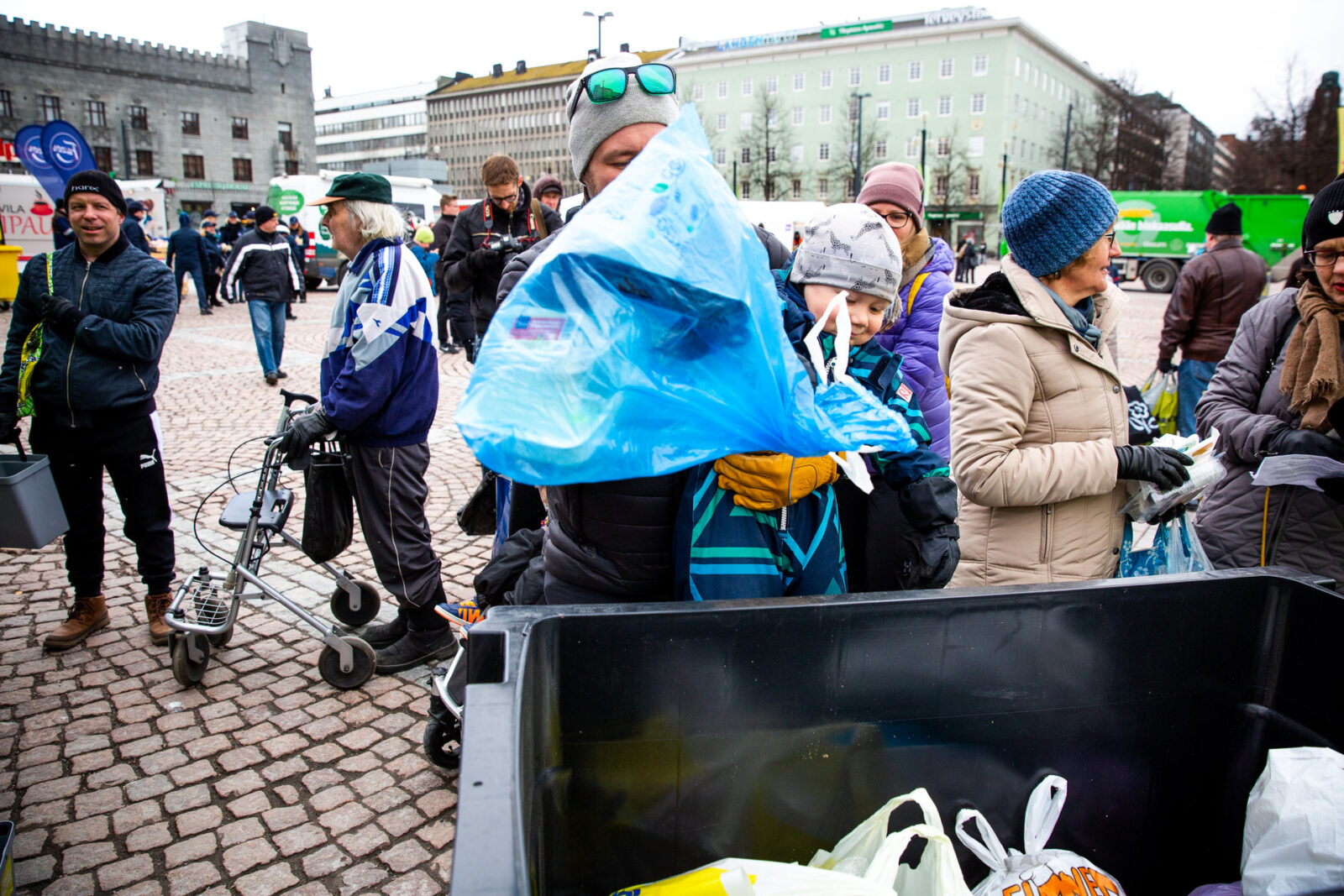 Pikkulapsi heittää sinistä roskapussia jäteastiaan