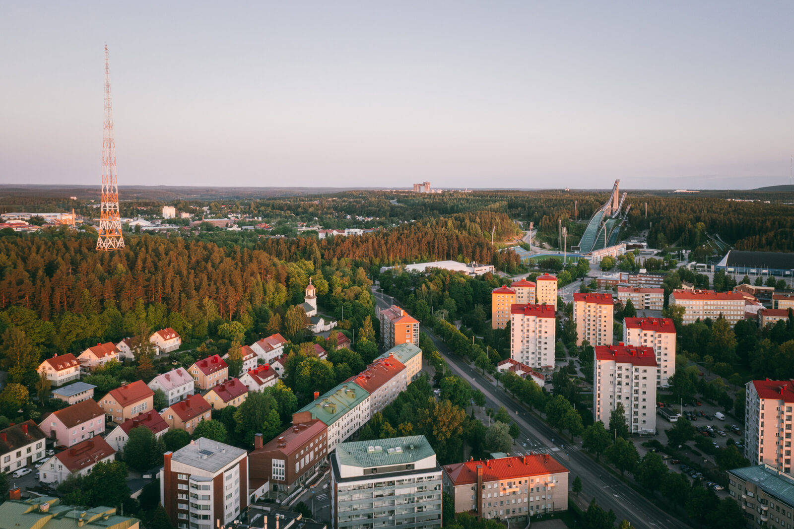 Ilmakuva Lahden keskustasta, jossa näkyy etualalla rakennuksia ja takana hyppyrimäet ja radiomasto