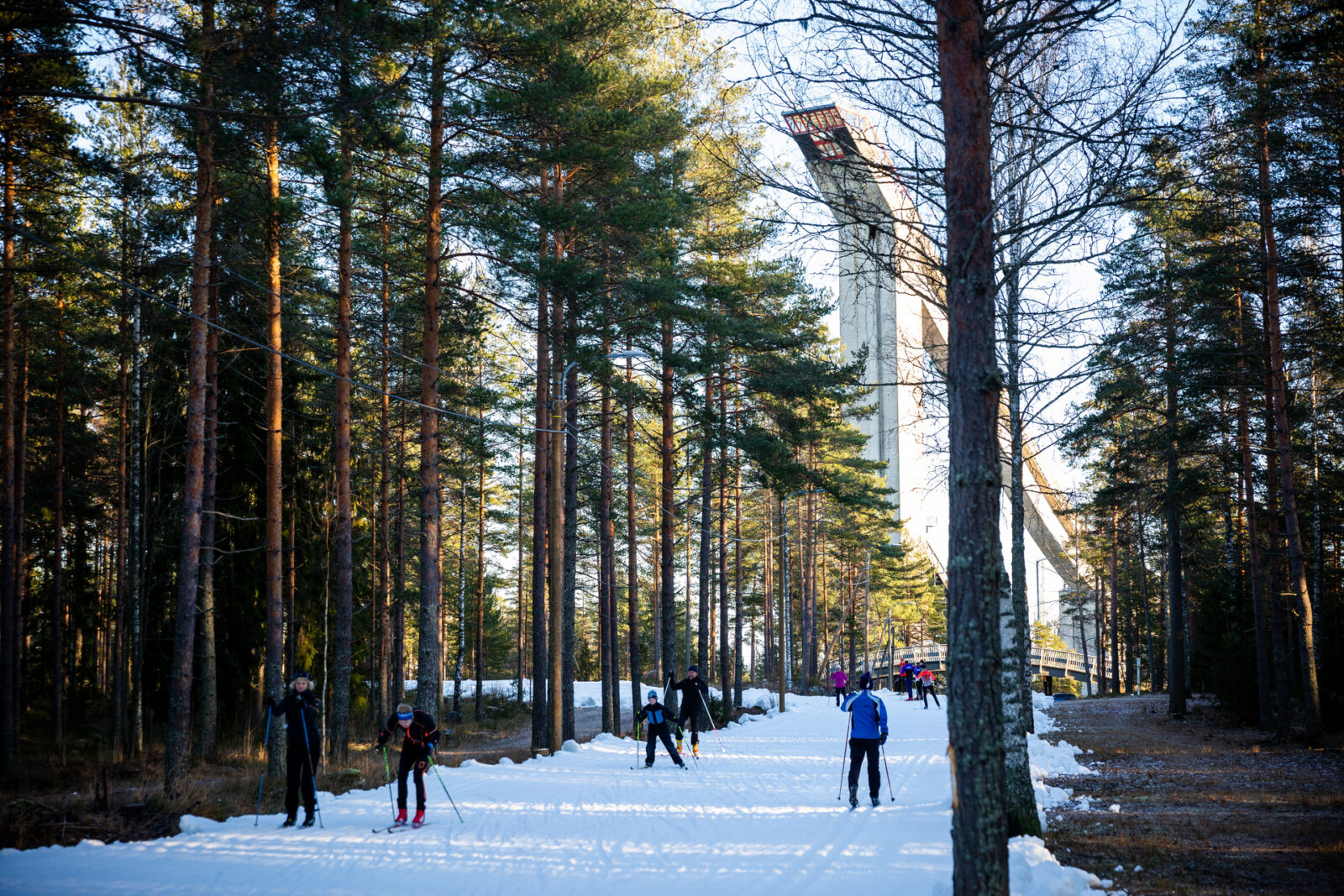 Lahtelaisia hiihtämässä ensilumenladulla, taustalla hyppyrimäet